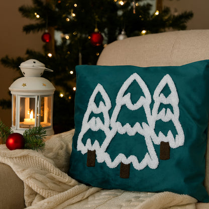 Teal pillow with pine tree design on a couch with Christmas decorations in the background