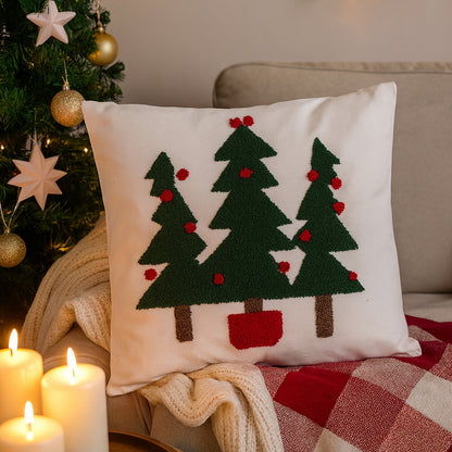 Decorative pillow with Christmas tree design on a couch next to a Christmas tree and candles.