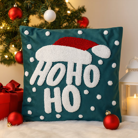 Decorative pillow with 'HO HO HO' text and Santa hat design in front of a Christmas tree.