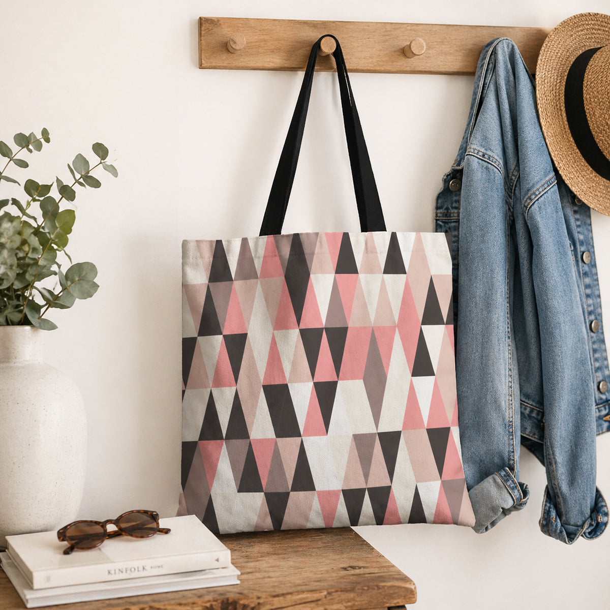 Tote bag with geometric pattern hanging on a hook with a plant, books, and jacket in the background.