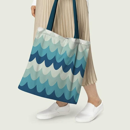 Women holding A tote bag with a wave pattern in shades of blue and white, with navy blue handles.