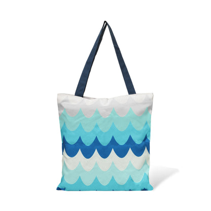 A tote bag with a wave pattern in shades of blue and white, with navy blue handles.