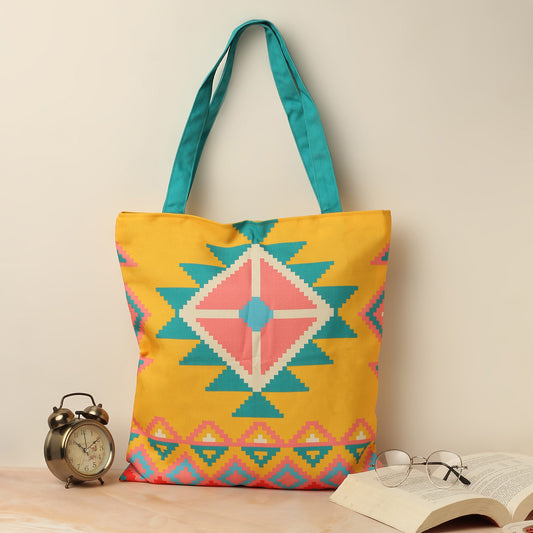 A vibrant tote bag with a yellow and blue base, adorned with a lovely pink and turquoise design.