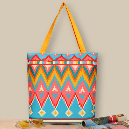 Colorful tote bag with geometric pattern in yellow,red,teal color with yellow color matching handle on a table with sunglass ad a magzine nearby, perfect for adding a pop of style to your outfit.