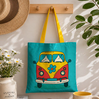 Tote bag with a colorful van design hanging on a wall next to a plant and mug.