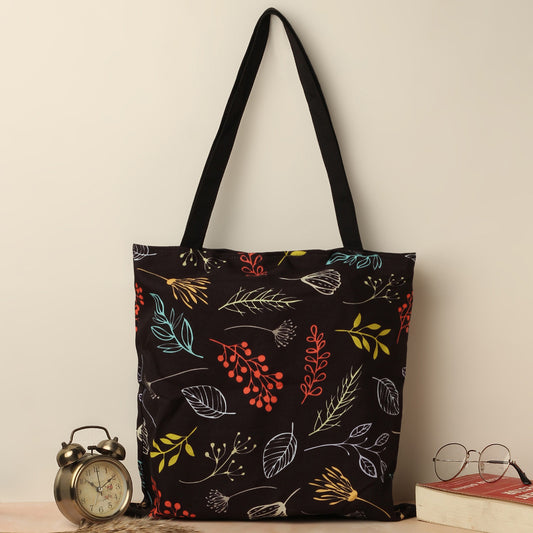 A black tote bag adorned with vibrant leaves and flowers, adding a pop of color to its elegant design.