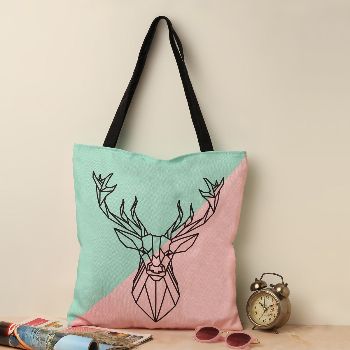 A stylish tote bag in pink and green with a deer head design. Perfect for adding a touch of nature to your outfit.