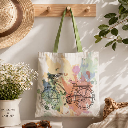 Tote bag with bicycle design hanging on a hook with a plant and hat in the background