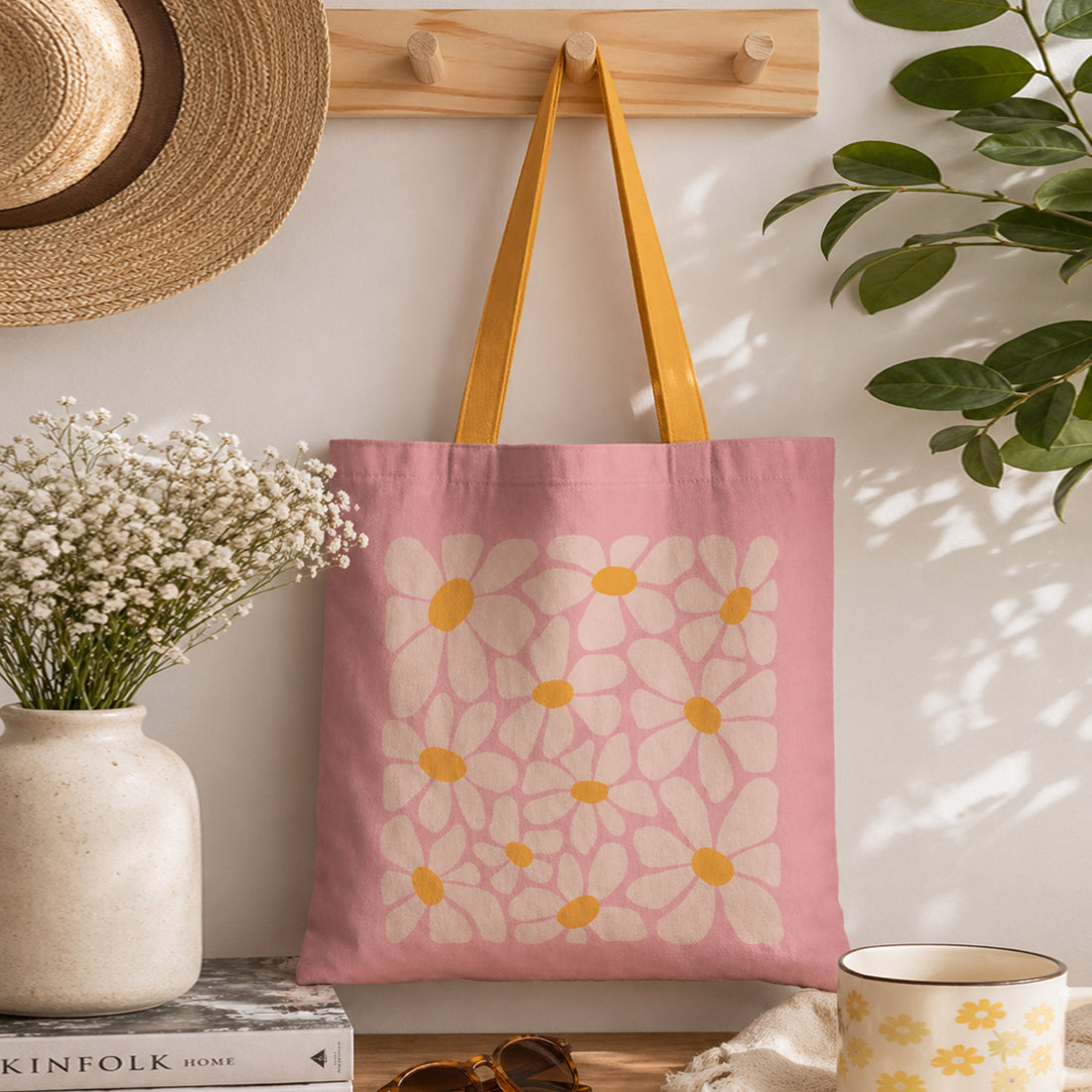 Pink tote bag with floral design hanging on a wooden hook, surrounded by decor items.