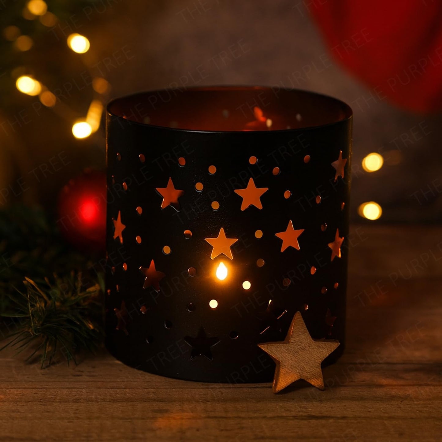 Black candle holder with star designs on a wooden surface, surrounded by festive decorations.