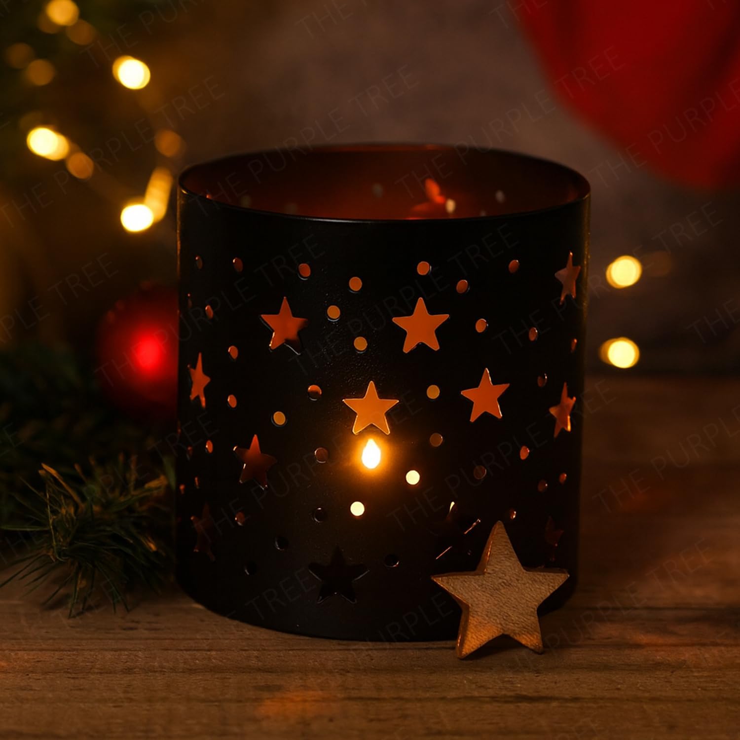 Black candle holder with star designs on a wooden surface, surrounded by festive decorations.