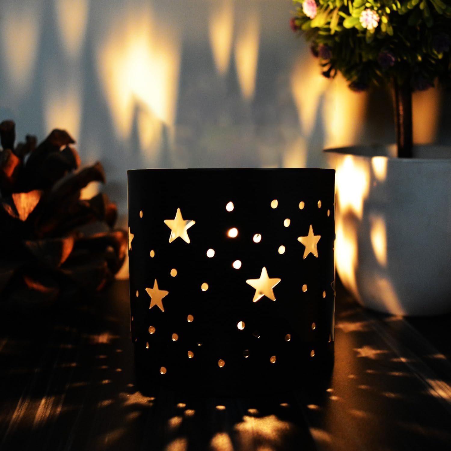 Black candle holder with star designs casting shadows on a surface