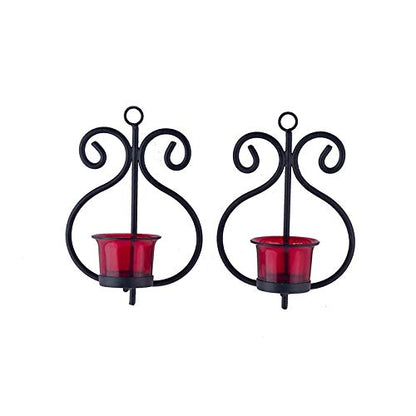 Two red candle holders with black metal accents on a wooden table.
