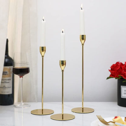 Table set with three gold candles, wine, and food