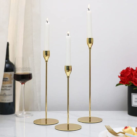 Table set with three gold candles, wine, and food