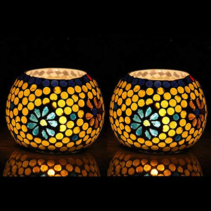 Two yellow glass tealights on black background.