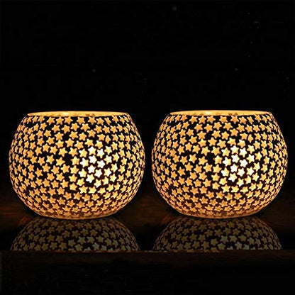 A pair of tealights, one white and one black, resting on a table.