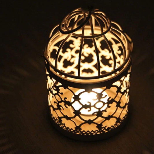 A cozy scene: a tiny candle flickers inside a bird cage, casting a warm glow.