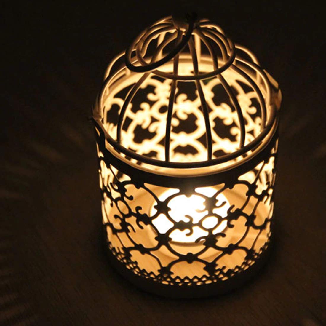 A cozy scene: a tiny candle flickers inside a bird cage, casting a warm glow.