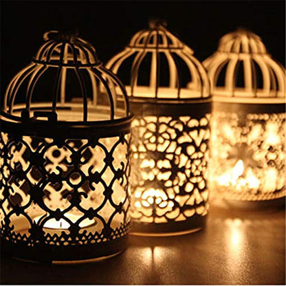 A small candle flickers inside a bird cage, casting a warm glow in the dimly lit space.
