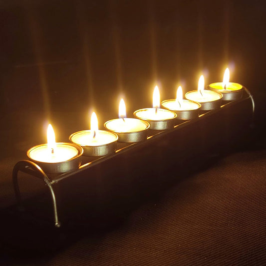  A row of lit candles on a metal stand.