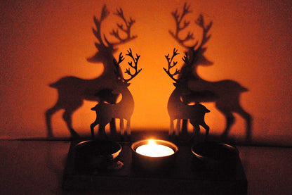 Two deer silhouettes illuminated by a candle in the dark night.