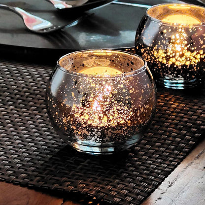 Glass tealight holders with candles glowing inside.