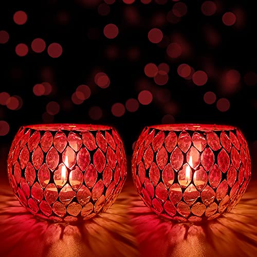 Two red glass tealights glowing on a table.