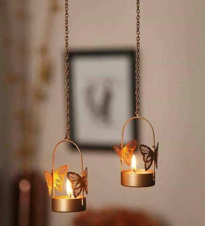 Two tealights with butterfly designs hanging from them, creating a whimsical and enchanting ambiance.