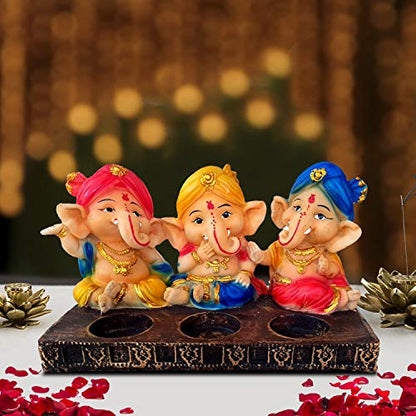 Three Ganesha statues displayed on a wooden tray.