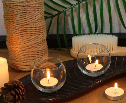 Glass bowl with lit candle inside, casting a warm glow.