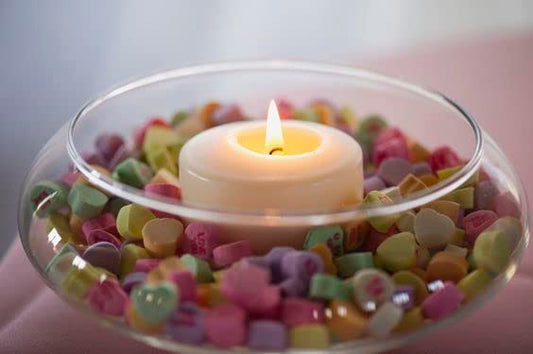 Seashells and candles arranged in a decorative bowl, evoking a coastal ambiance.
