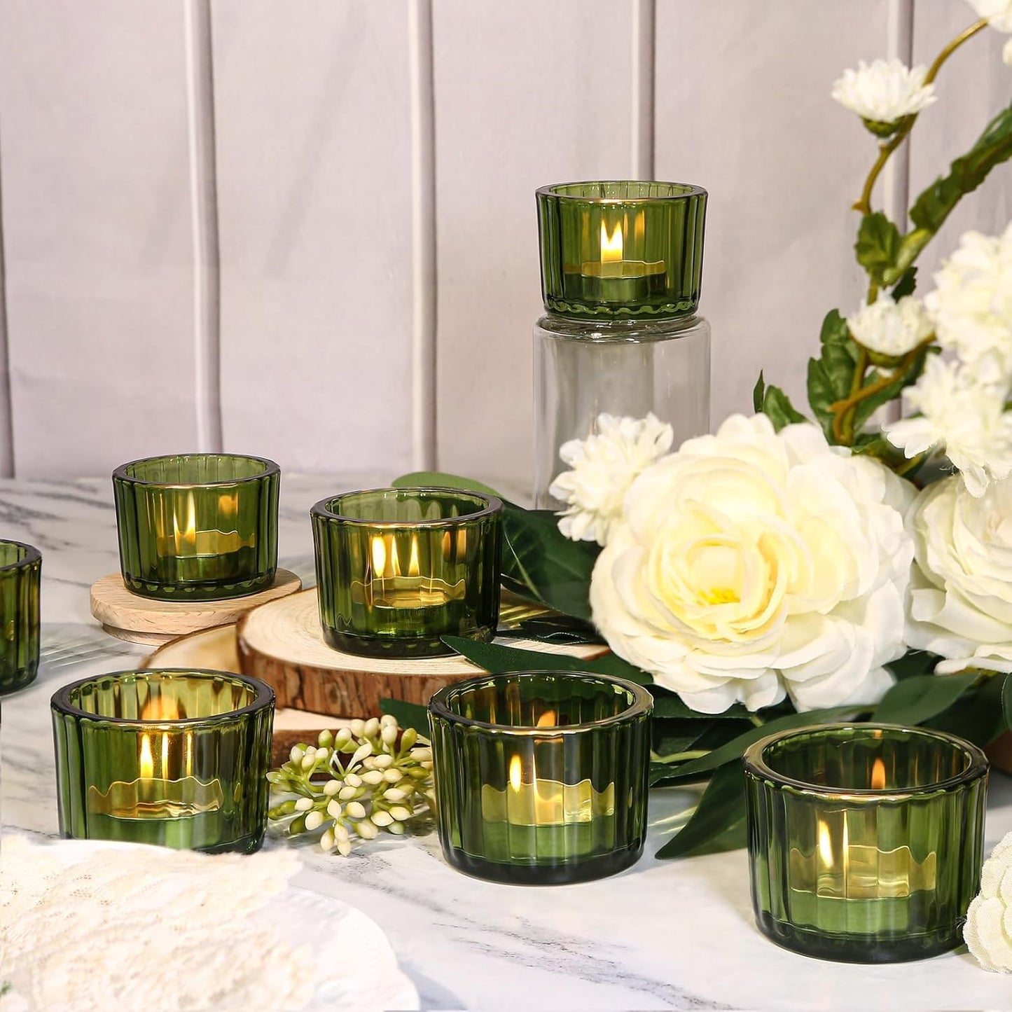 Green glass candles with white flowers on a table