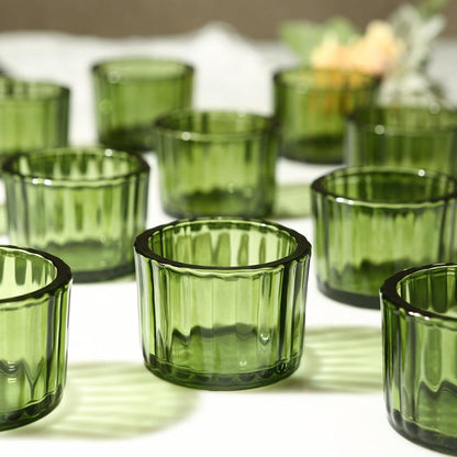 Green glass votive holders on a white surface