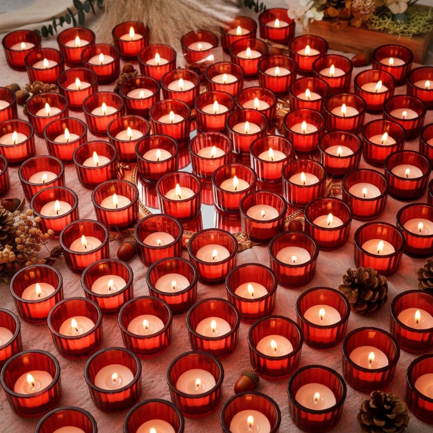  numerous red candles in holders arranged on a textured surface with decorative elements.