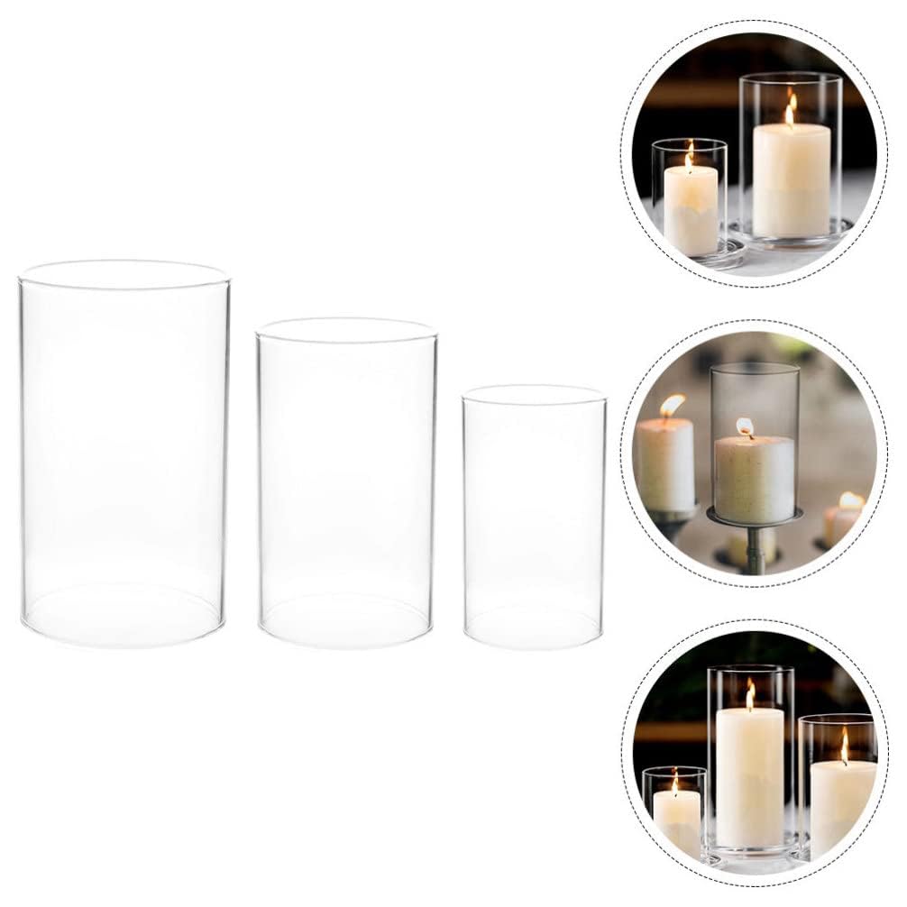Three glass candles surrounded by white flowers.