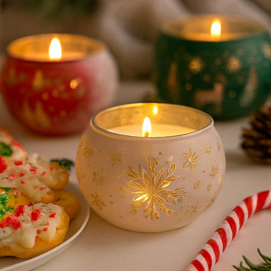 Decorative candles with snowflake designs on a table with cookies and a straw.