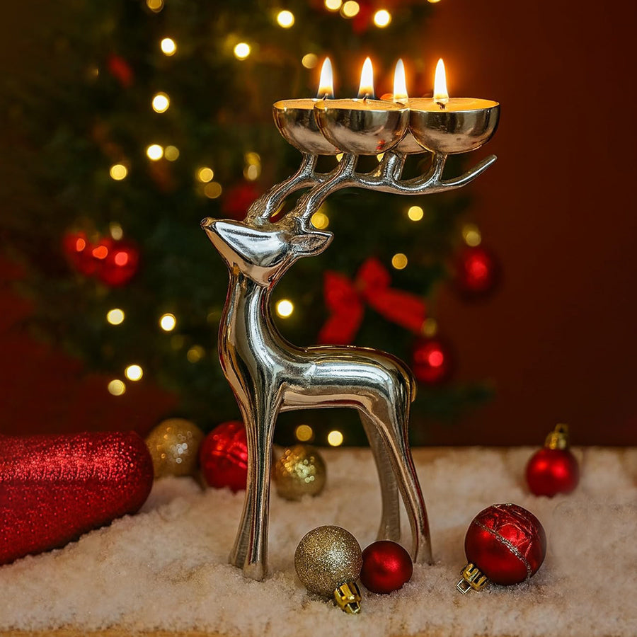 Silver reindeer candle holder with lit candles in front of a Christmas tree.