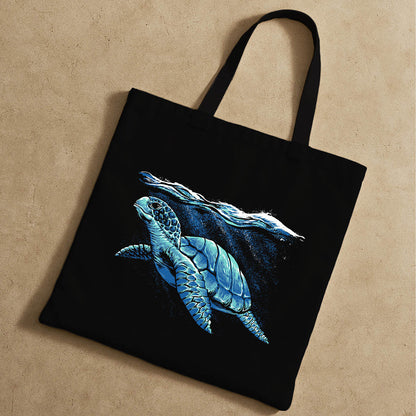 A black tote bag showcasing a sea turtle swimming in the ocean, emphasizing marine life.