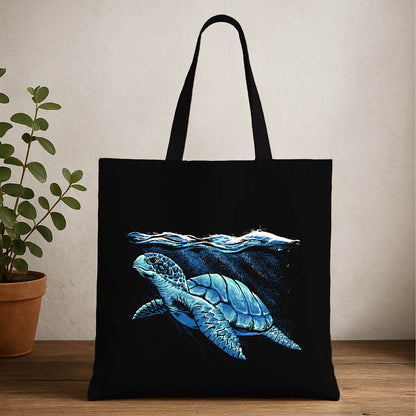 A black tote bag featuring a sea turtle swimming gracefully in the ocean.