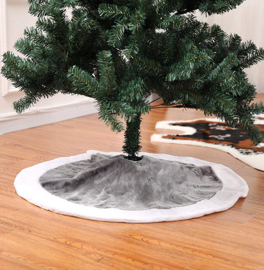 Christmas tree with a gray base and white trim on a wooden floor.