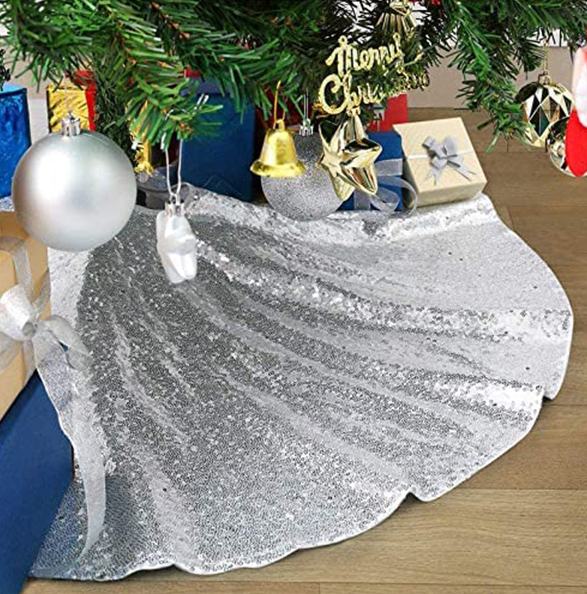 Silver glittery tree skirt under a Christmas tree with ornaments.