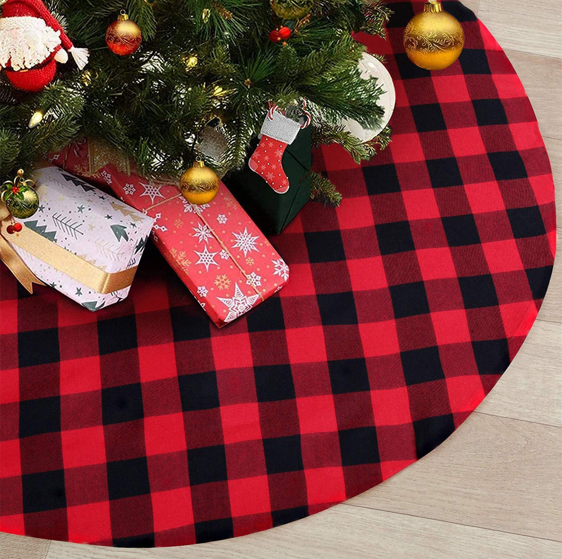 Red and black checkered Christmas tree skirt with a tree, presents, and stockings underneath.