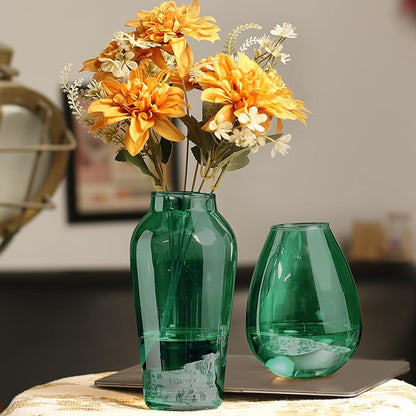 Green vase filled with flowers on desk.