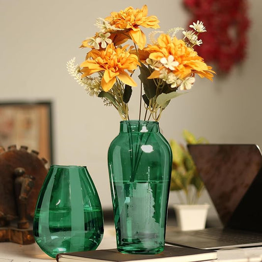 A beautiful green vase filled with colorful flowers sitting on a desk.