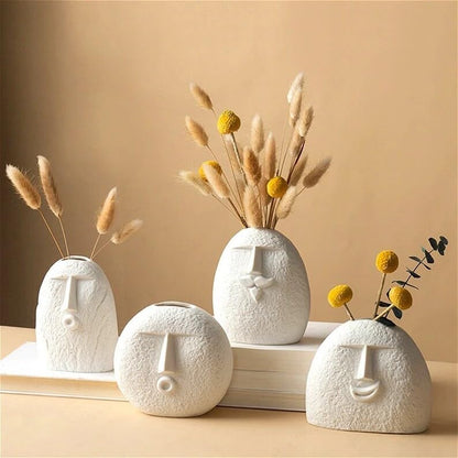  Decorative vases with face illustrations positioned on a table.