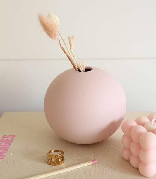 A pink vase with a lit pink candle and a matching candle holder.