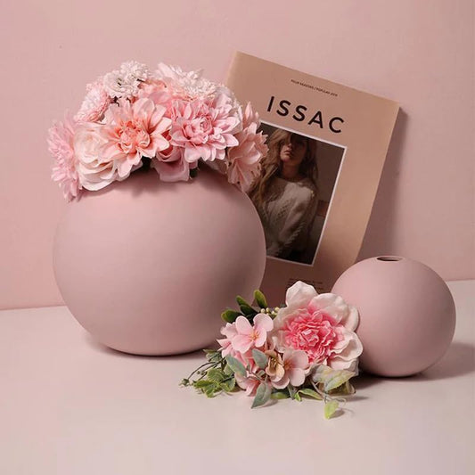 Decorative pink vase with flowers and magazine on table