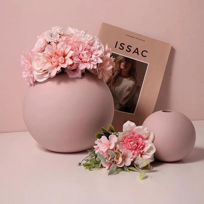 Decorative pink vase with flowers and magazine on table