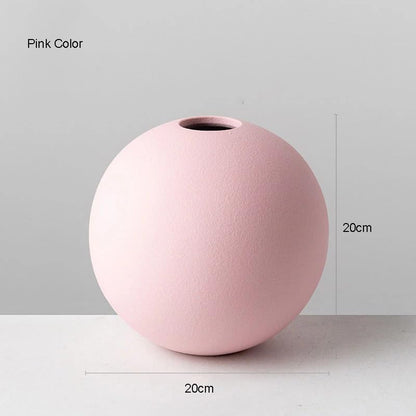 A pink vase shaped like a ball with measurements.
